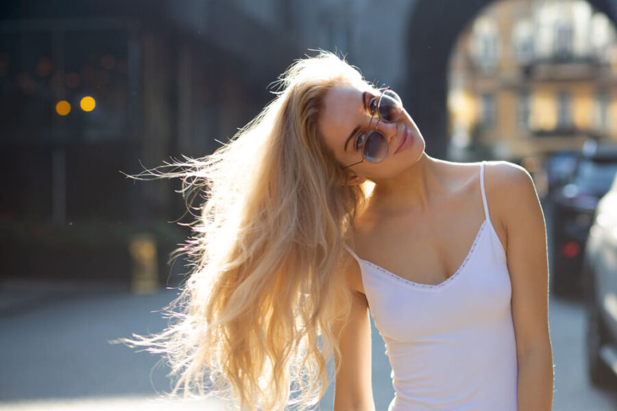 Blondes Model mit Sonnenbrille und weißem Oberteil