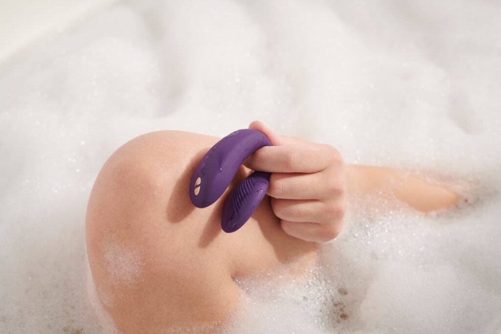 Eine Frau in der Badewanne mit Vibrator im Hand