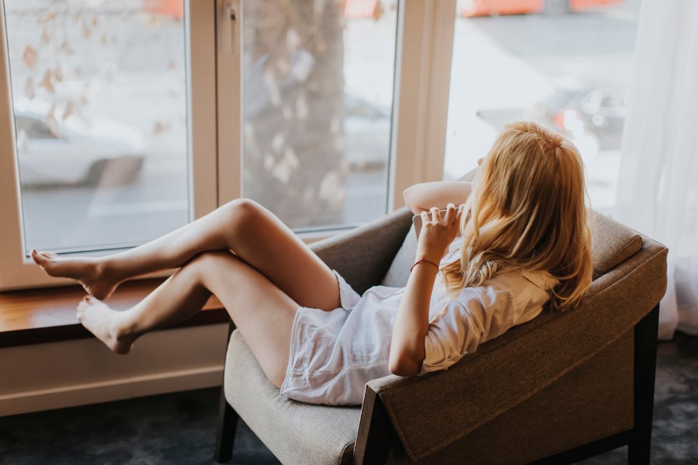Lady sitting on the chair beside the window