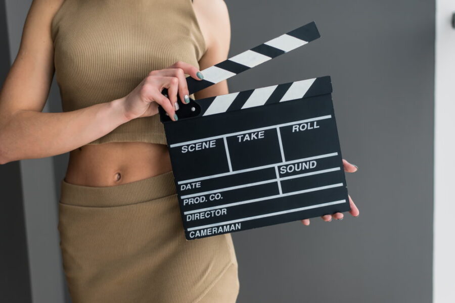 Hot escort lady with clapperboard in hand