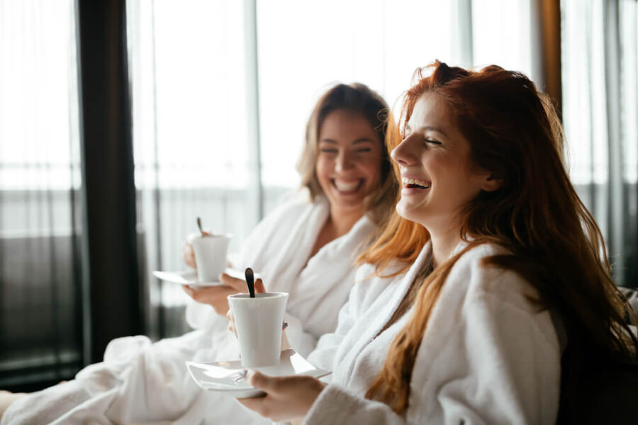 Two women wearing bath robes drinking coffee