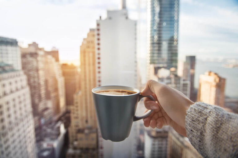 Woman holding coffee in front of skyscrapers