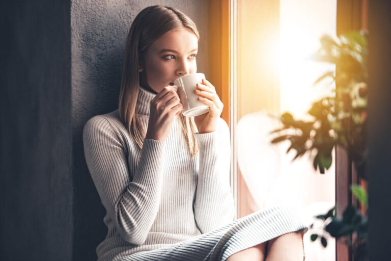 Woman drinking coffee in front of a window