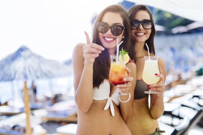 Two women wearing bikinis holding cocktails